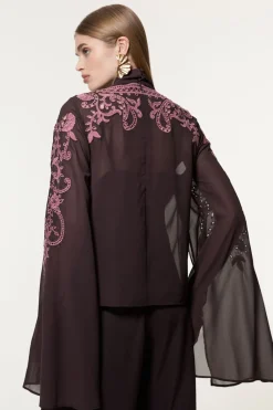 Chemisier long tissé en georgette aux découpes ajourées et orné de perles, avec un col noué et des manches dramatiques.