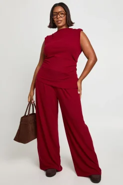 Haut avec épaulettes, détails plissés, ourlet asymétrique et pantalon à jambes larges