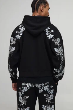 Hoodie à capuche oversize et cubique, avec surpiqûres apparentes, broderie florale et fermeture éclair intégrale.