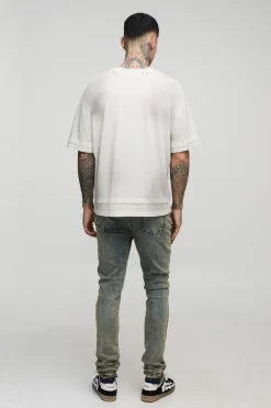 Jeans skinny longs empilés avec applique croisée et empiècement