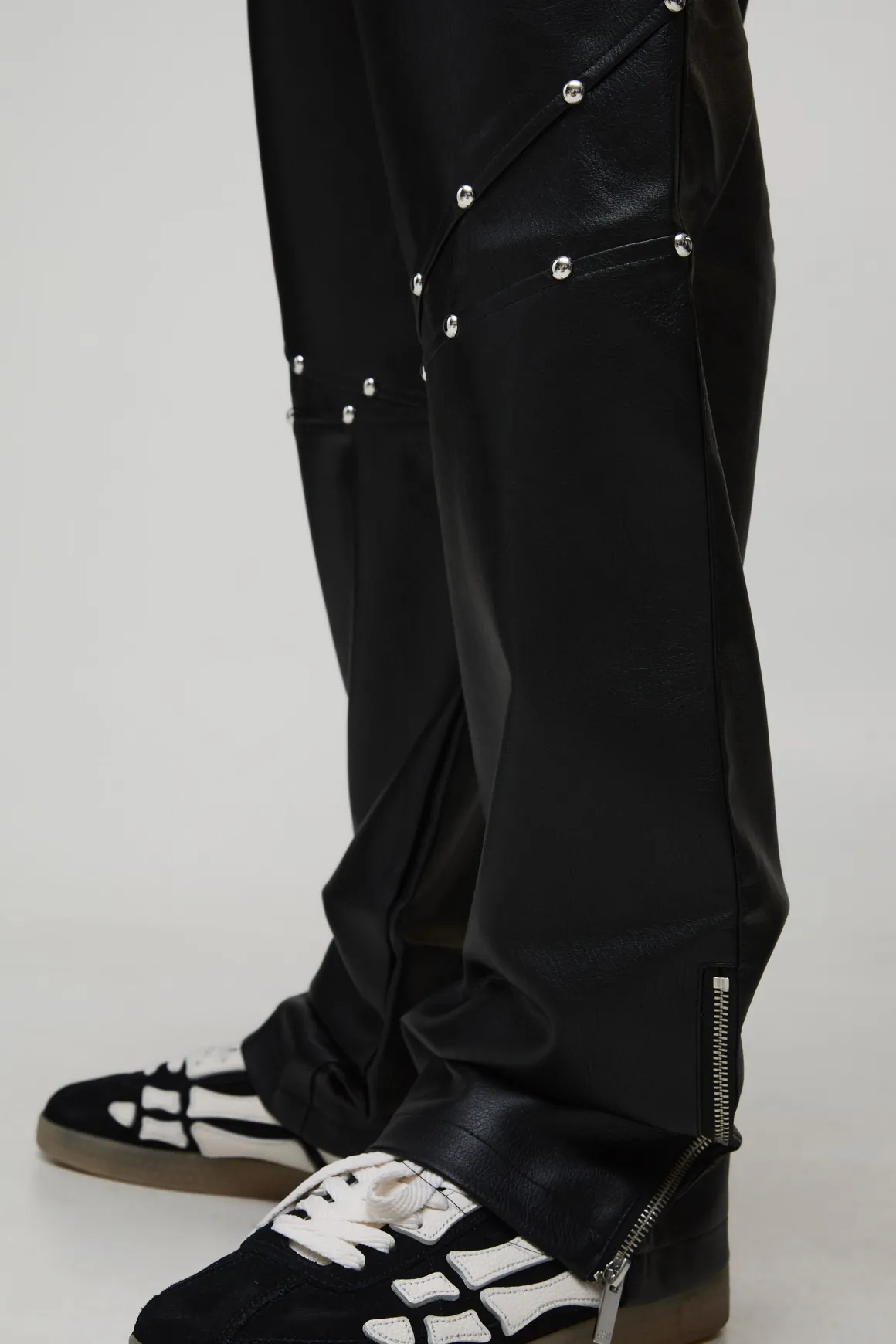 Pantalon long clouté à l'aspect cuir, ourlet zippé et coupe décontractée