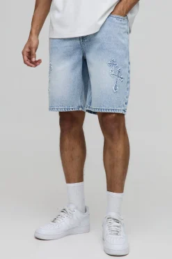 Shorts en denim bleu à coupe décontractée, effet "stone washed" et appliqué en forme de croix