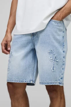 Shorts en denim bleu à coupe décontractée, effet "stone washed" et appliqué en forme de croix