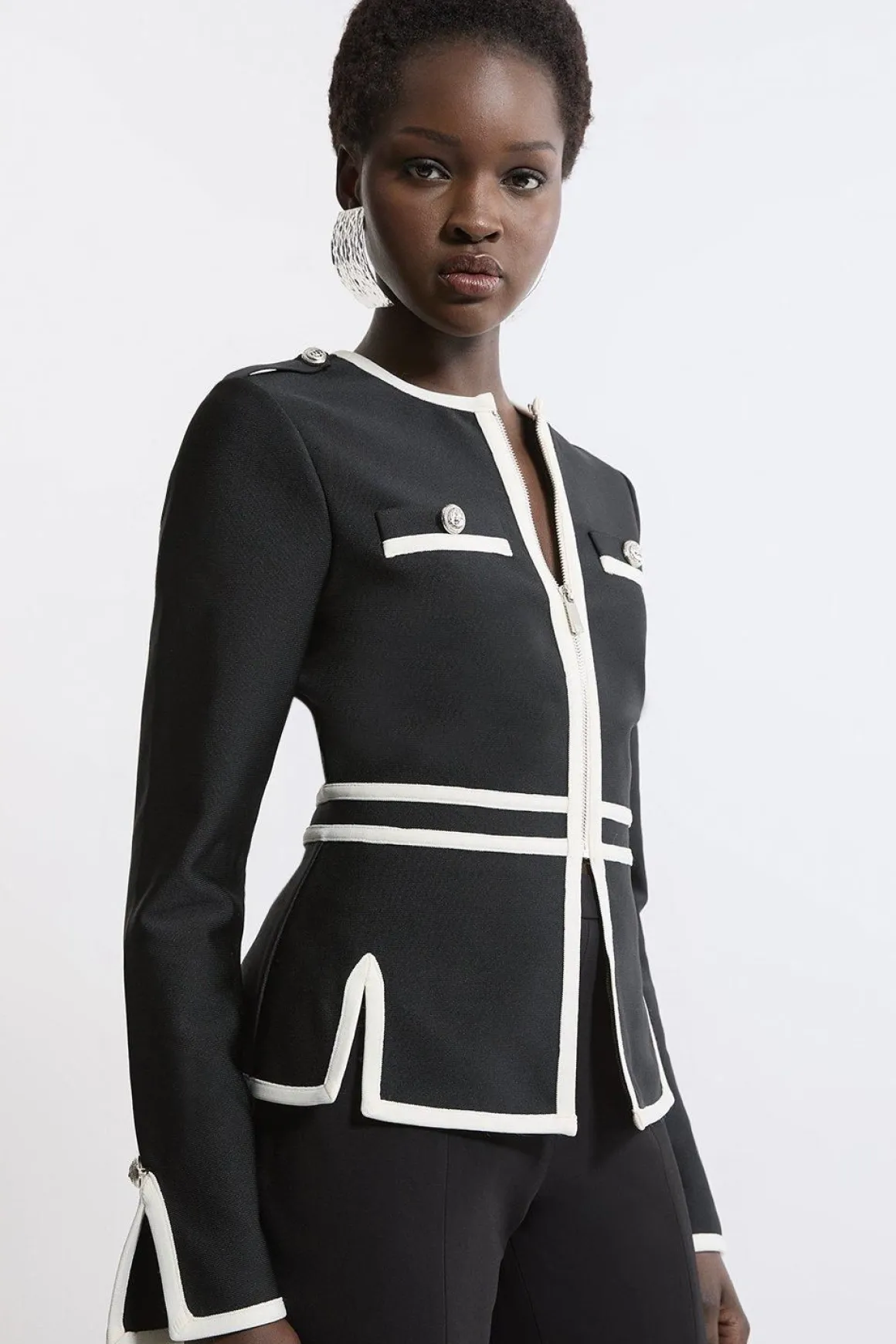 Veste en maille à ourlet fendu, effet bandage sculptant la silhouette, avec passepoils contrastés militaires.