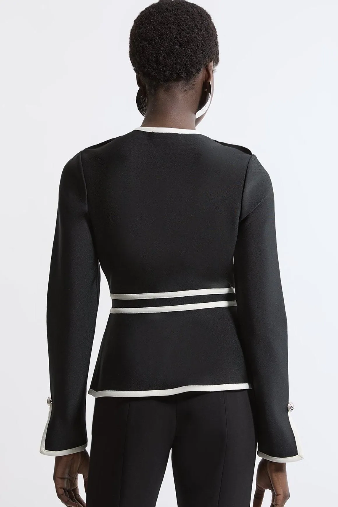 Veste en maille à ourlet fendu, effet bandage sculptant la silhouette, avec passepoils contrastés militaires.