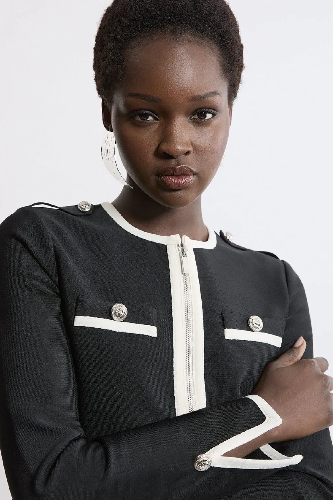 Veste en maille à ourlet fendu, effet bandage sculptant la silhouette, avec passepoils contrastés militaires.