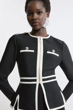 Veste en maille à ourlet fendu, effet bandage sculptant la silhouette, avec passepoils contrastés militaires.